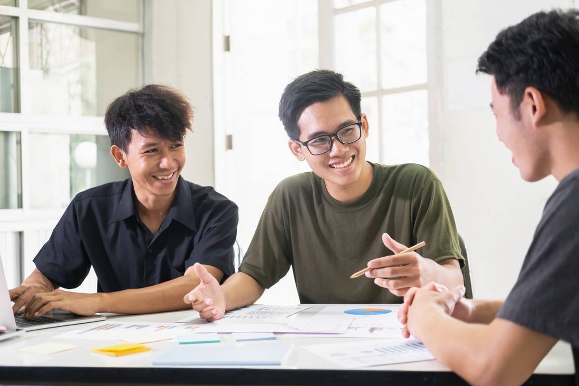 Three men at a table looking over work documents, working together