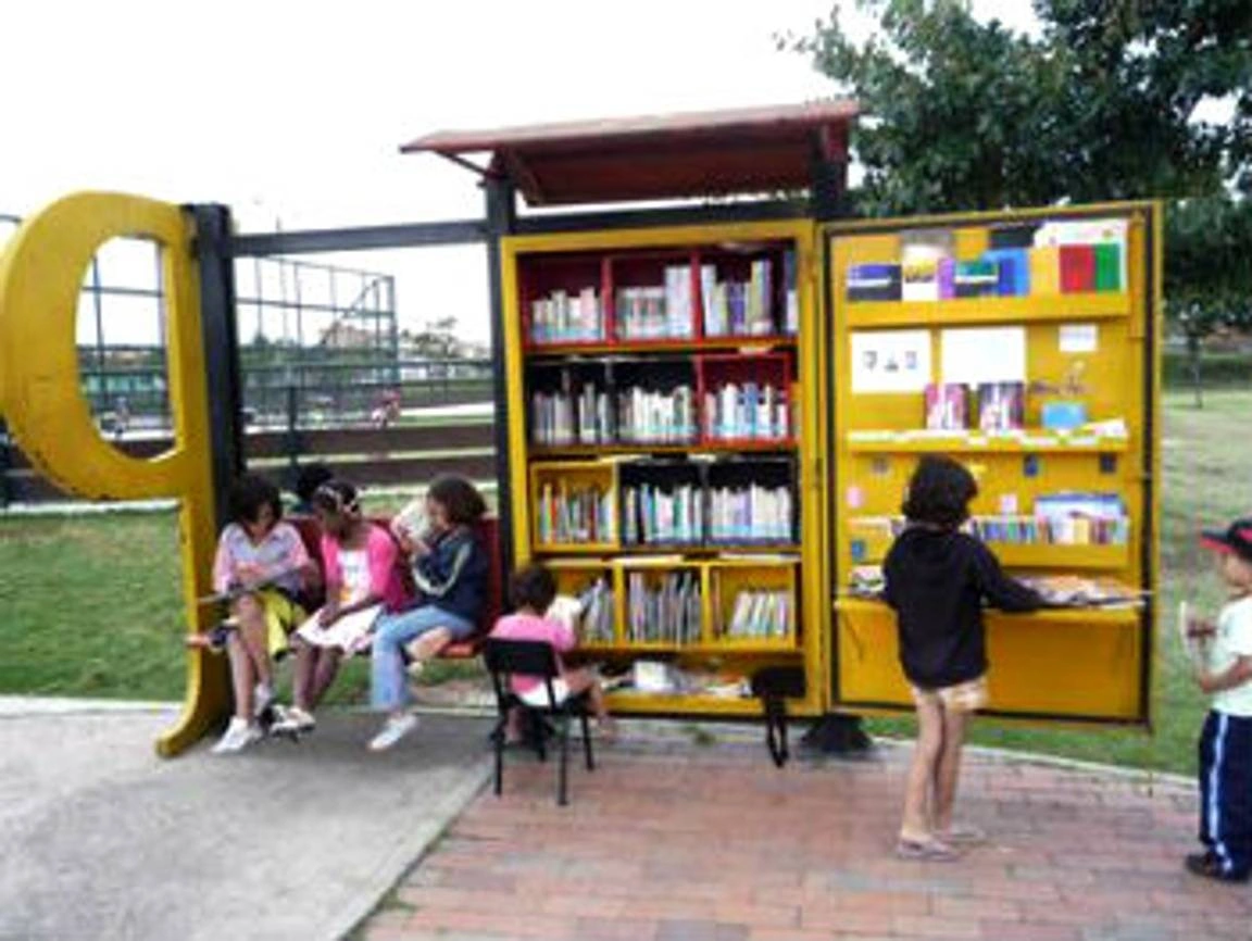 Group of kids picking up books and reading from a miniature library.