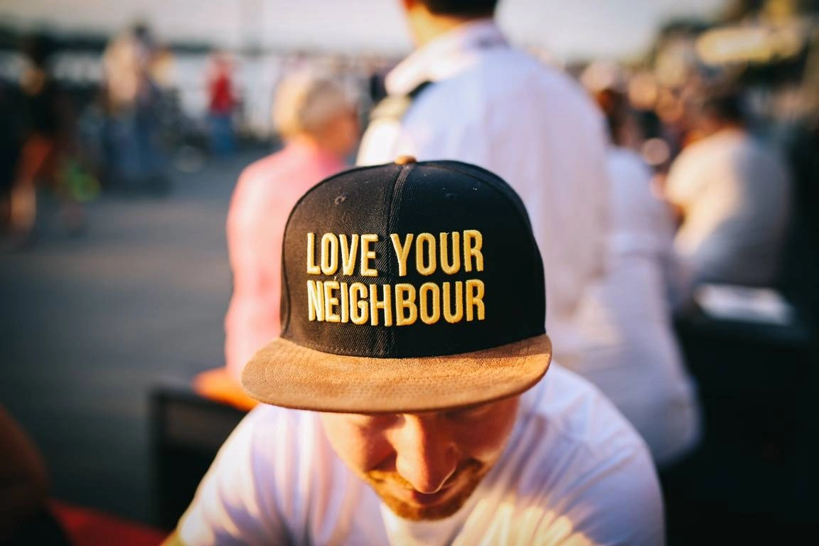 Rapaz com boné com os dizeres "Love Your Neighbor" (Ama o teu próximo, em português)