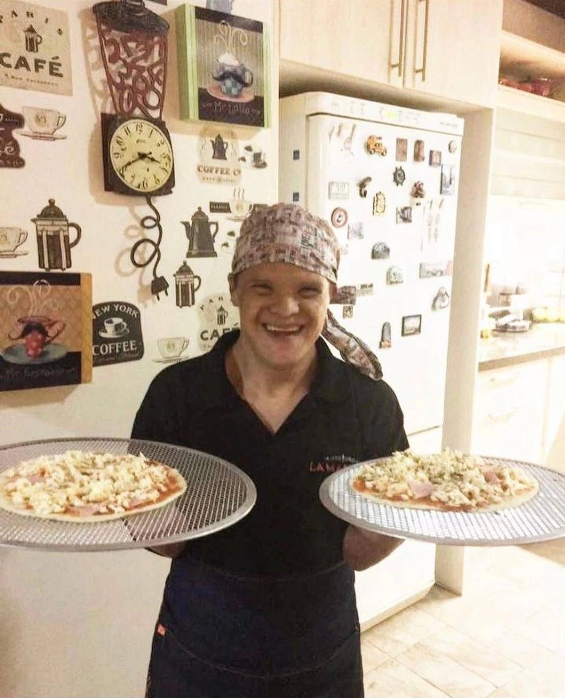 Alvarito sonriente, una de las personas del equipo llevando dos pizzas