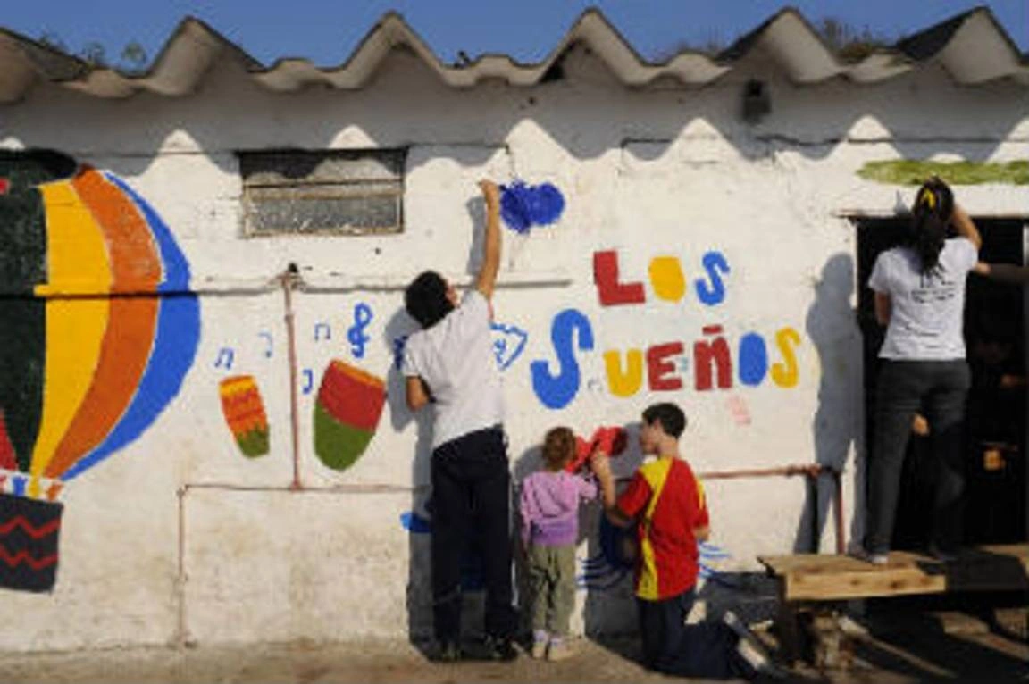 Voluntarios pintando la fachada de un colegio