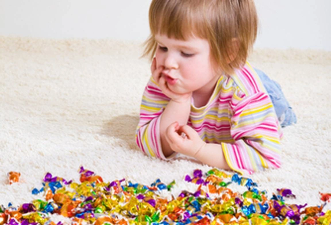 A toddler looking at her candy wrappers.