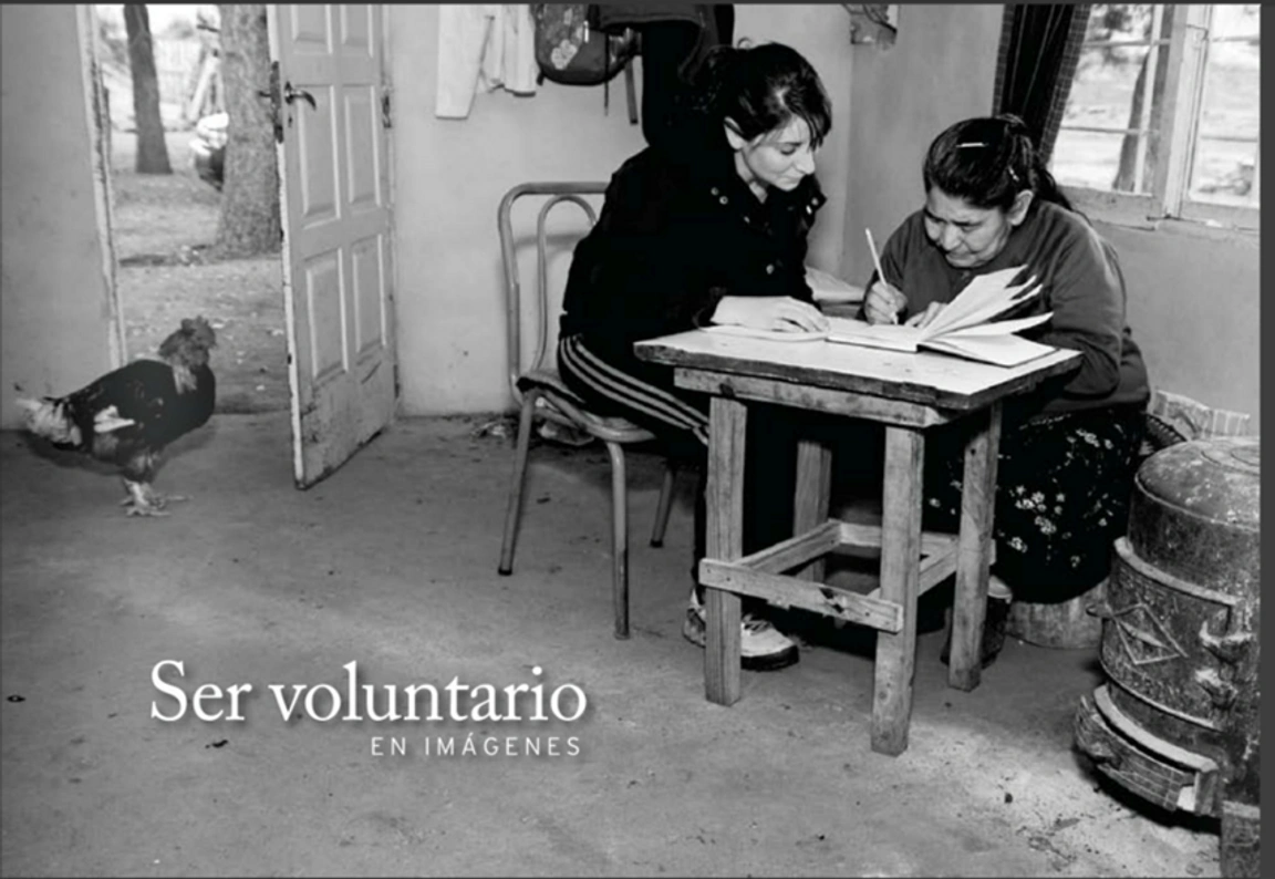Two women sitting in a house, reading a book and taking notes