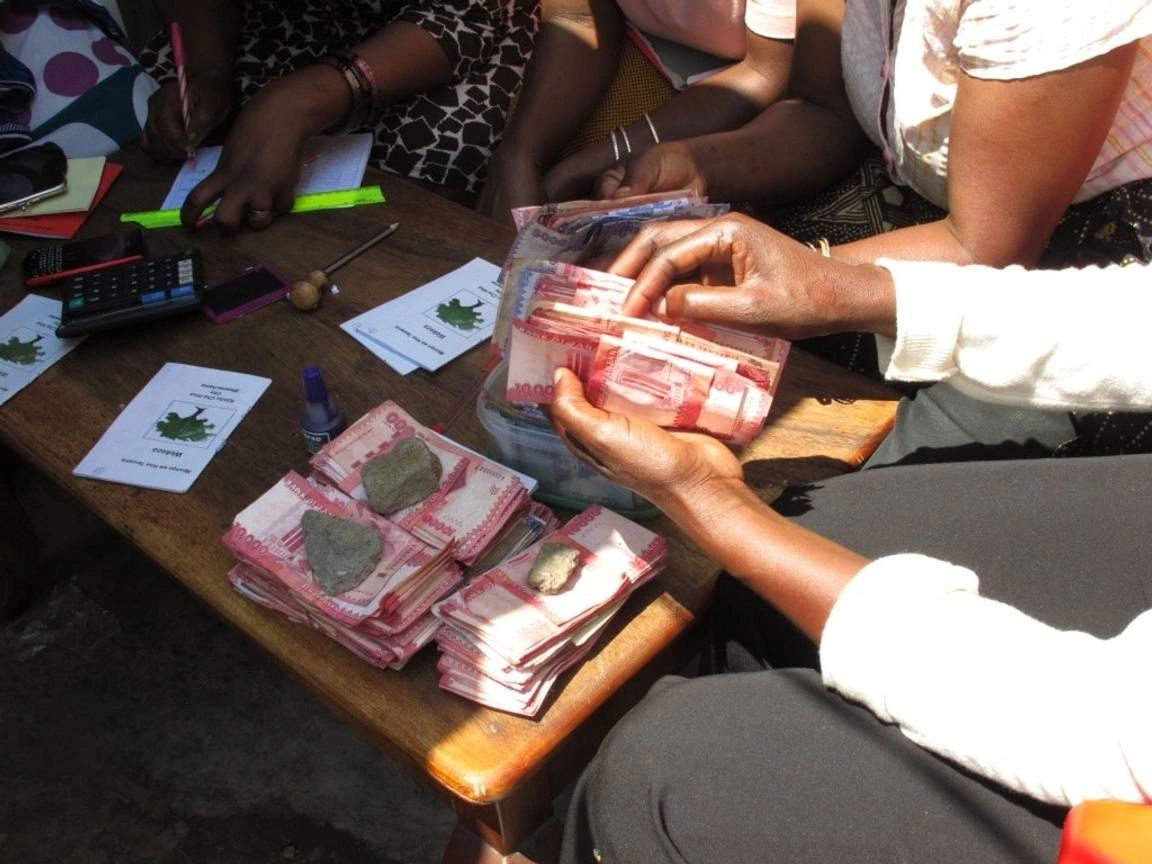 Pessoas de uma comunidade contam dinheiro em volta de uma mesa
