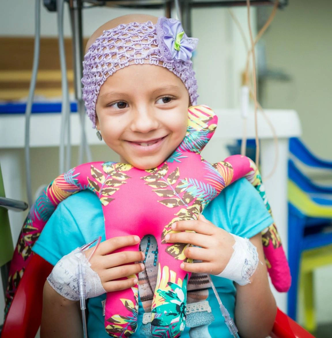 Niña con cáncer sonriendo mientras abraza un muñeco de abrazadores