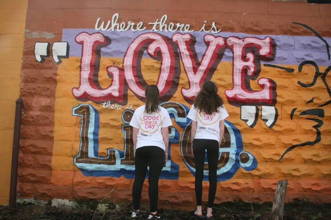 two women standing in-front of a wall mural