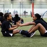 two young female soccer players doing a partner stretch