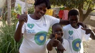 A group of people with their thumbs up pose with Idealist shirts on