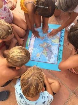 A group of children gather around a map that says Idealista on it.