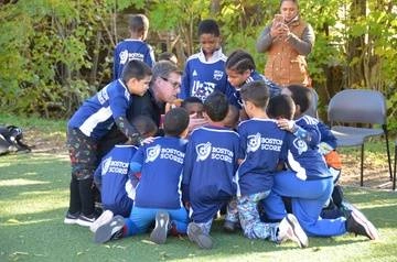 group of elementary school-aged male soccer players gathered around their coach in a huddle