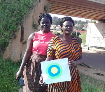 Two women pose with the Idealist logo between them.