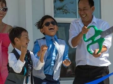 Woman, two small boys and man celebrate after cutting ribbon on home