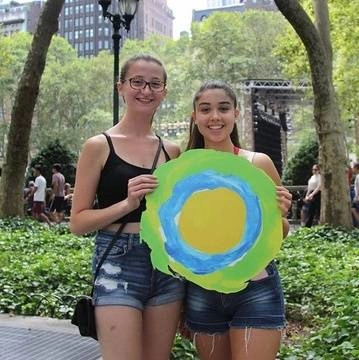Two women pose with the Idealist logo between them.