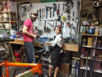 Bike shop manager Josh with a boy helping to fix bikes
