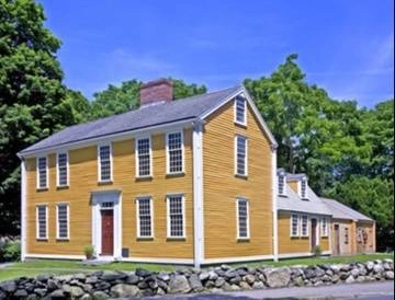 Yellow, colonial-era, two-story building with additions at back