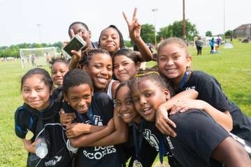 group of BIPOC children in America SCORES uniform on the side of a soccer field