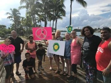 A group of people holding up the Idealist logo and other rally art.