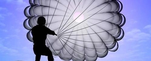A person sailing through the air on a parachute.