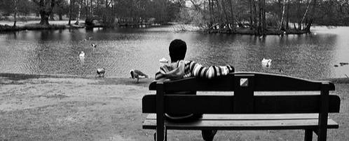 Someone sitting on a bench looking out at the water.