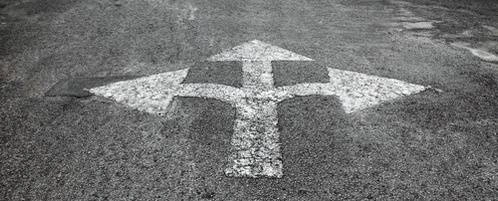 Close up of a pavement marking pointing in different directions.