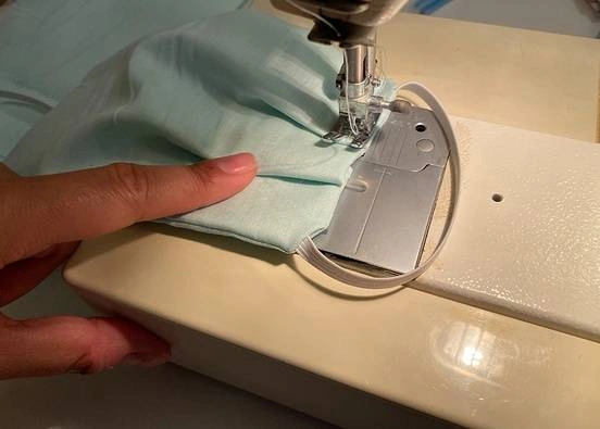A homemade face mask getting stitched in a sewing machine.
