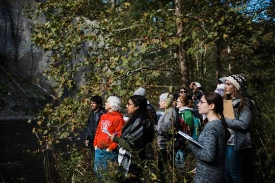 Group of students and faculty exploring an outdoor space near a waterfall