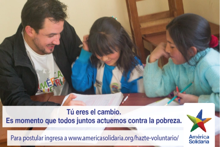 Un voluntario ayudando a dos niñas a hacer tareas