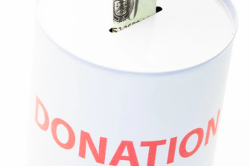 Una caja de donaciones y un billete entrando