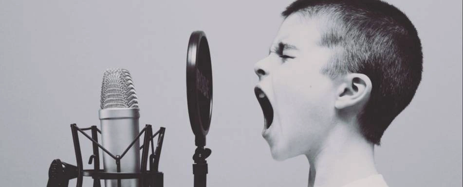 A boy yelling into a microphone.