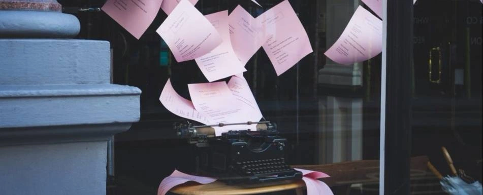 A type writer printing multiple pieces of pink paper.