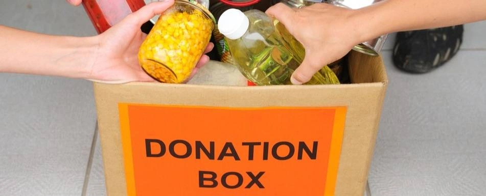People putting food in a donation box.