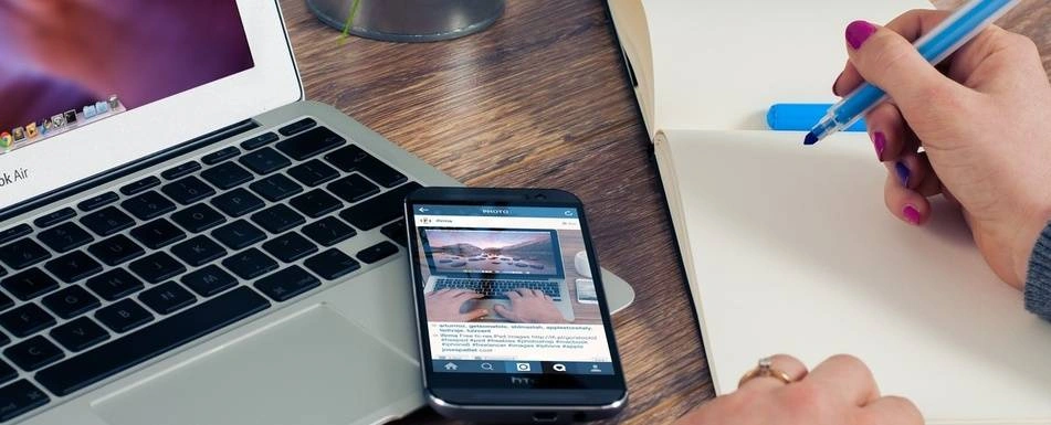 A smartphone on top of a laptop.