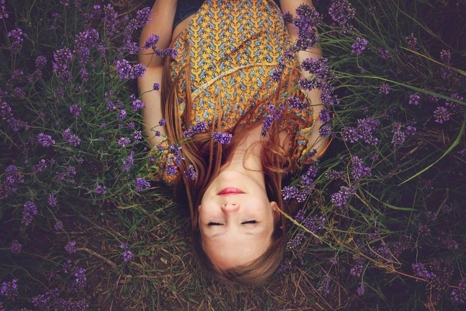 A woman rests in a field of purple flowers.
