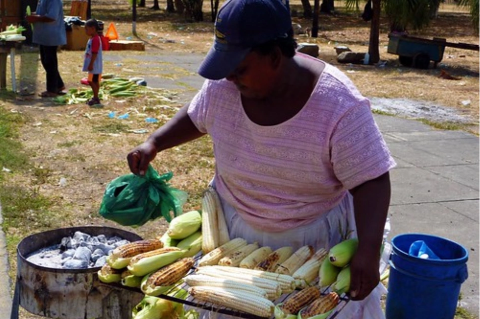 Mujer asando maíces para vender