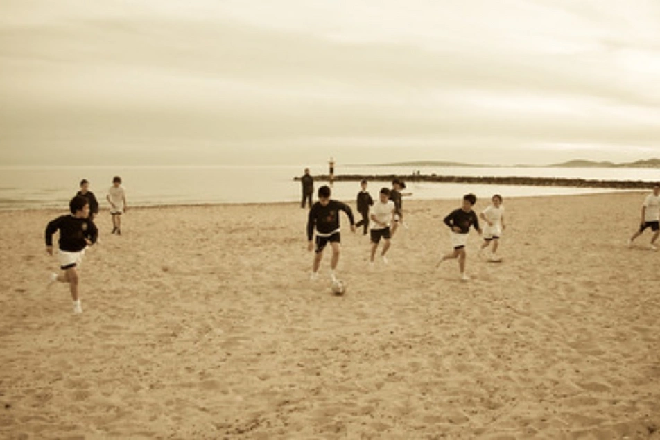 Niños jugando fútbol en una playa