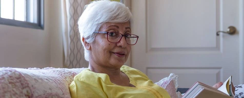 older woman with book on sofa