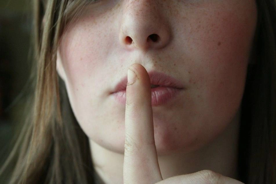 A woman pressing a finger to her lips.