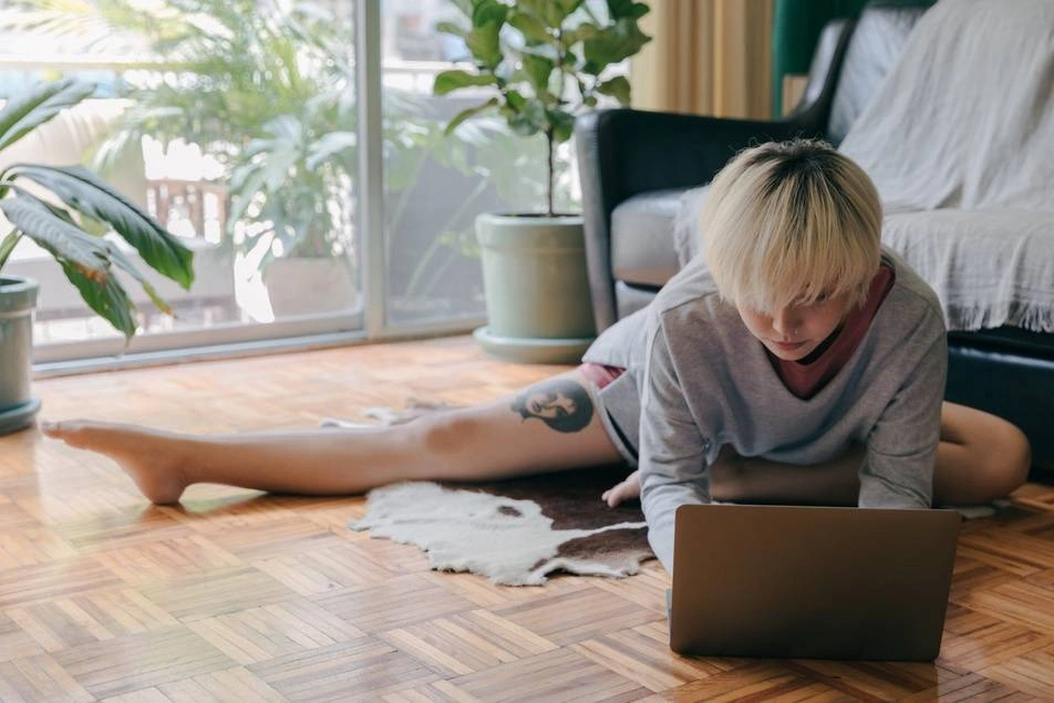 woman stretching on floor in front of laptop