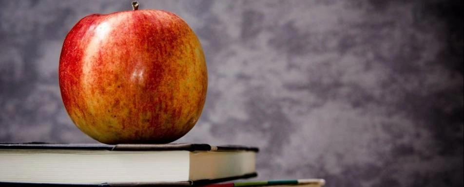 An apple on top of a book.