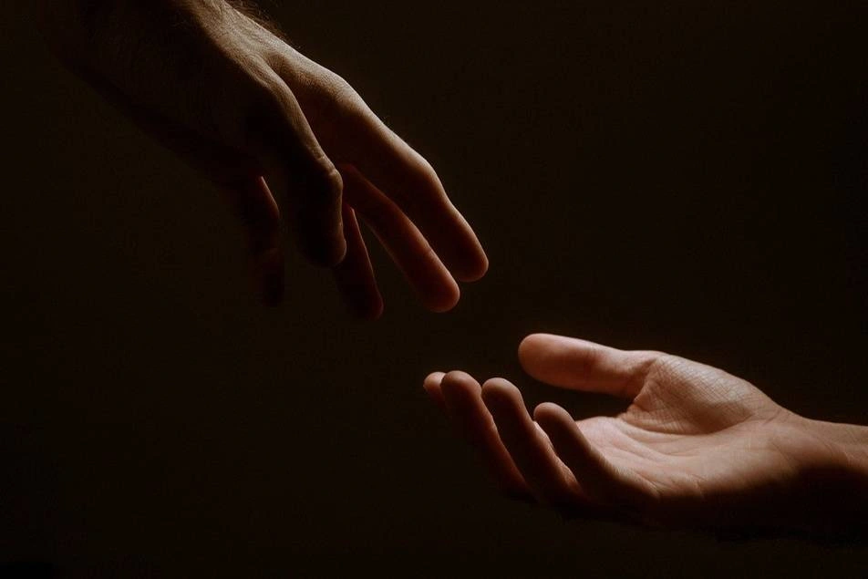 Two hands reach for each other.
