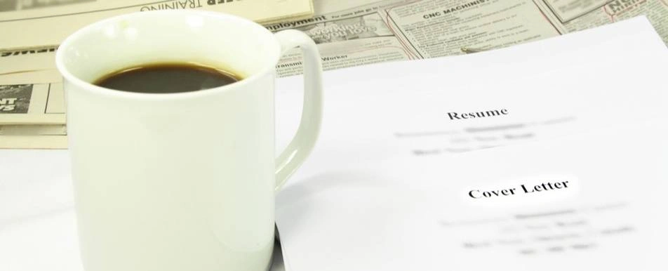 A resume and cover letter next to a cup of coffee.