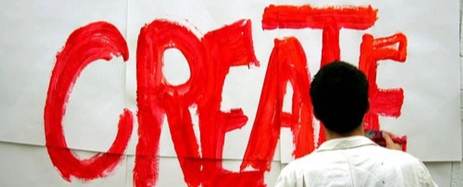 Someone painting the word create in red on a white wall.
