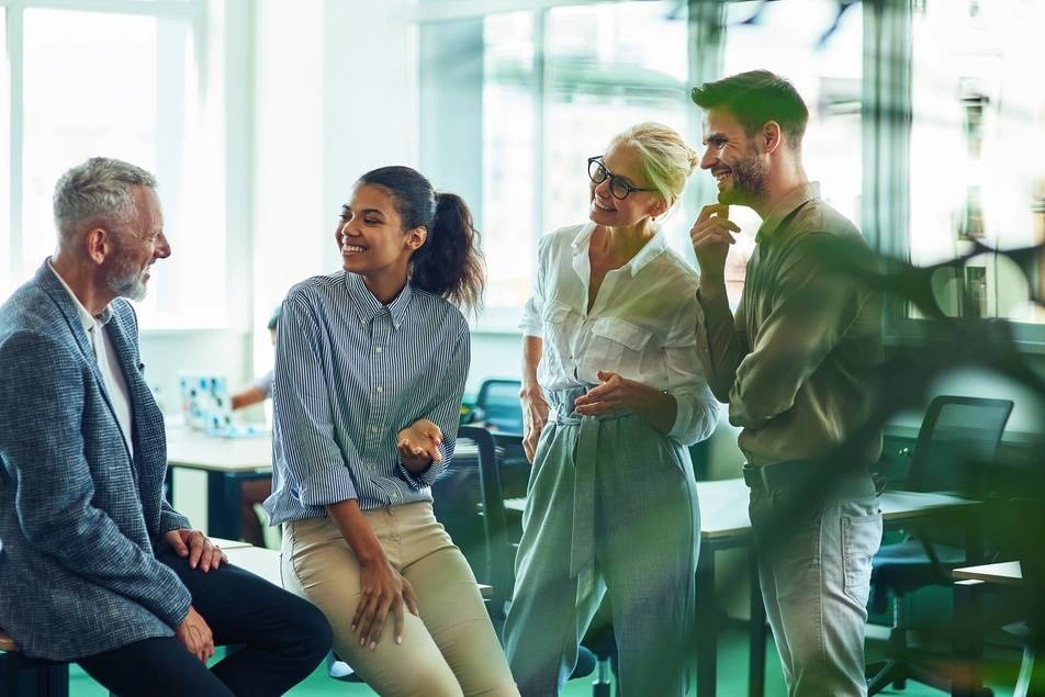 A photograph of a multigenerational workforce laughing in an office setting.