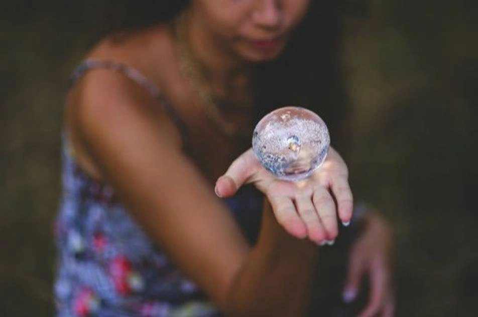 Mujer sosteniendo una bolita de cristal en la palma de su mano