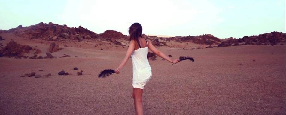 A woman dancing in the desert in a white slip.