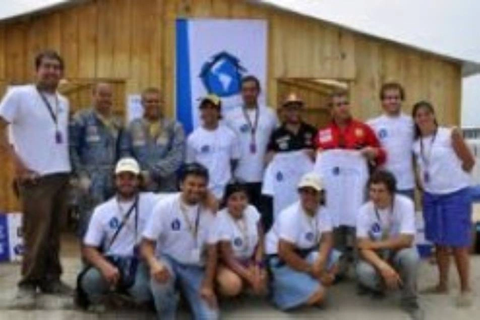 A group of volunteers in white shirts pose for a photo.