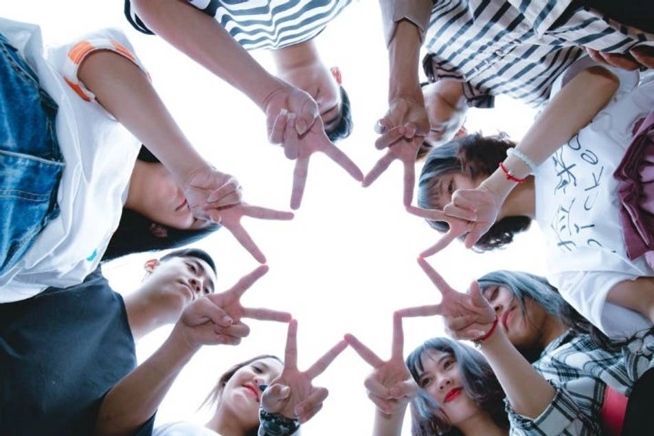 A group of children form a star with their fingers.
