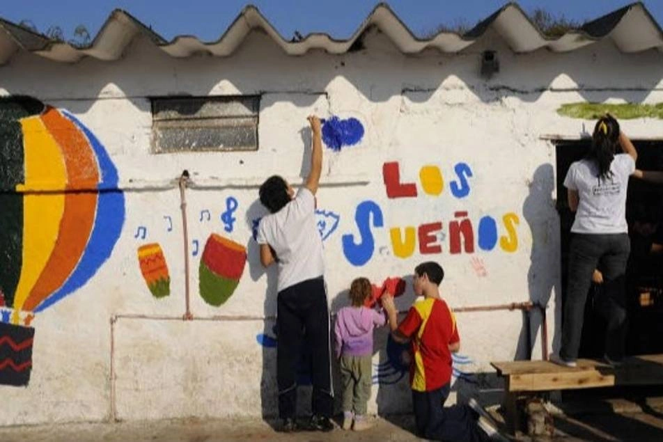 chicos y chicas pintando una fachada