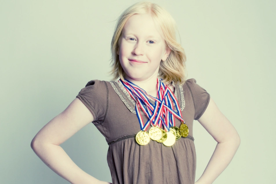 Una niña con varias medallas de oro colgadas de su cuello