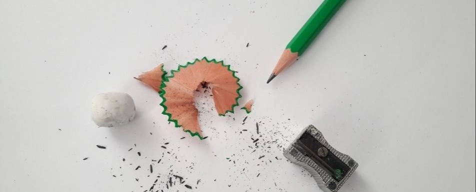 A pencil with a sharpener and pencil shavings.